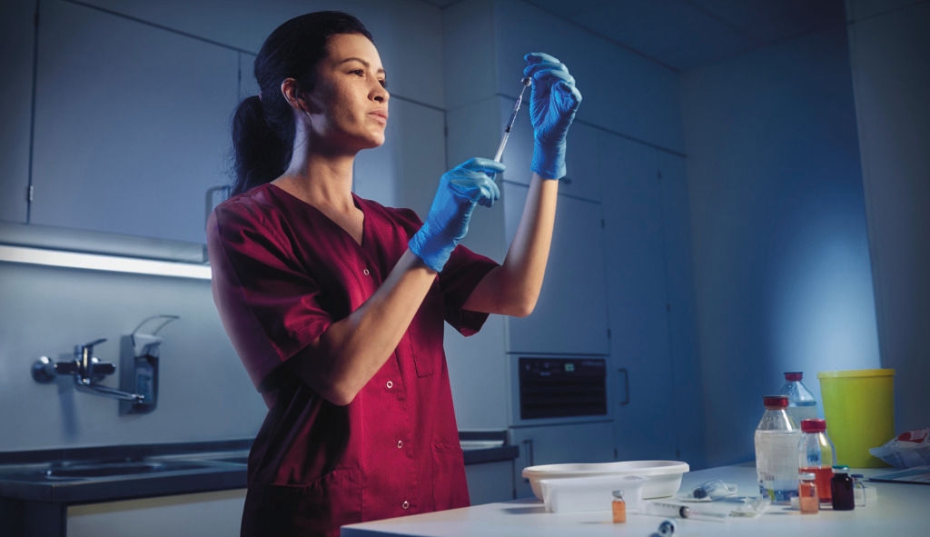 Pharmacist draws up syringe under lamina airflow